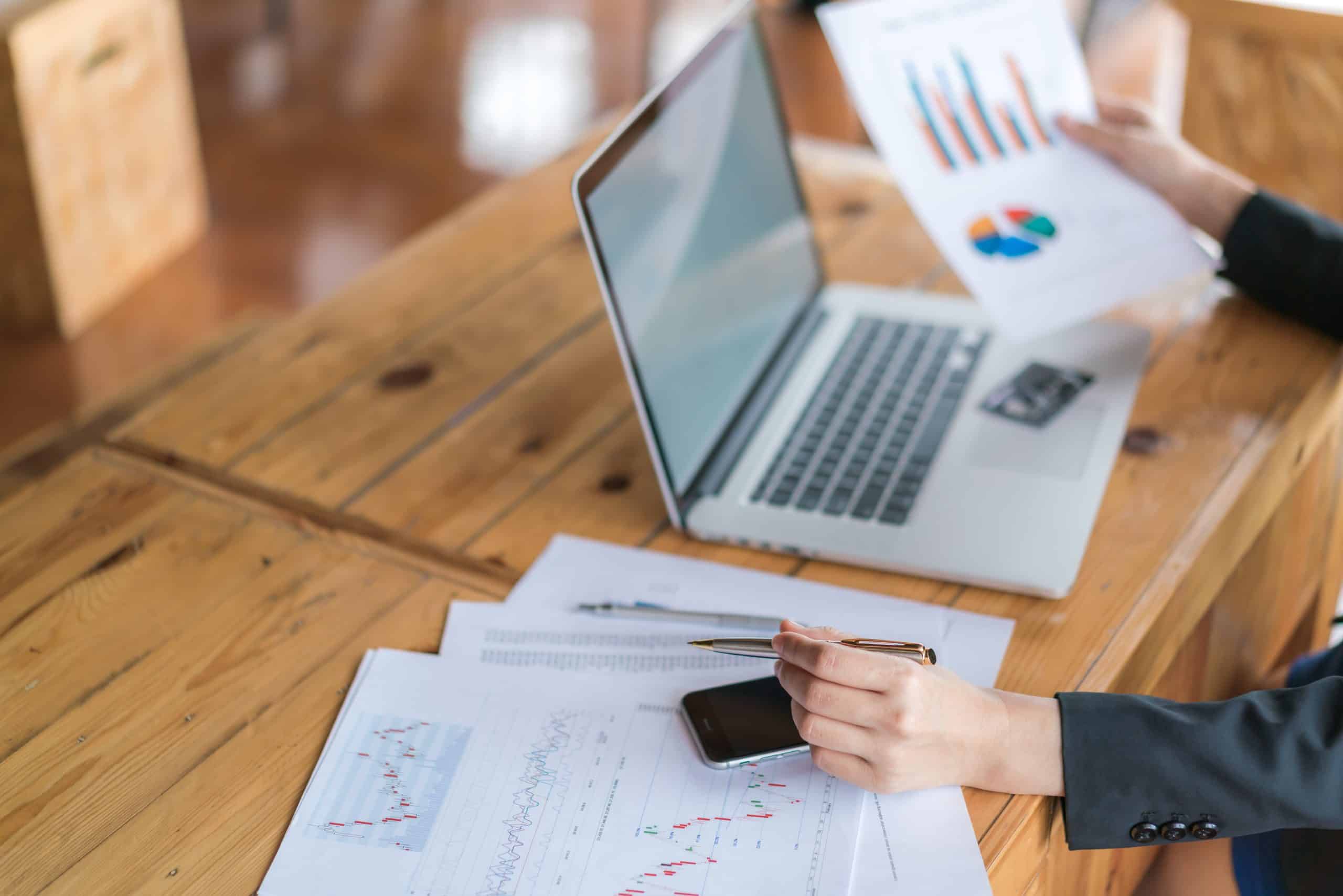 Business woman hand with Financial charts and laptop on the table